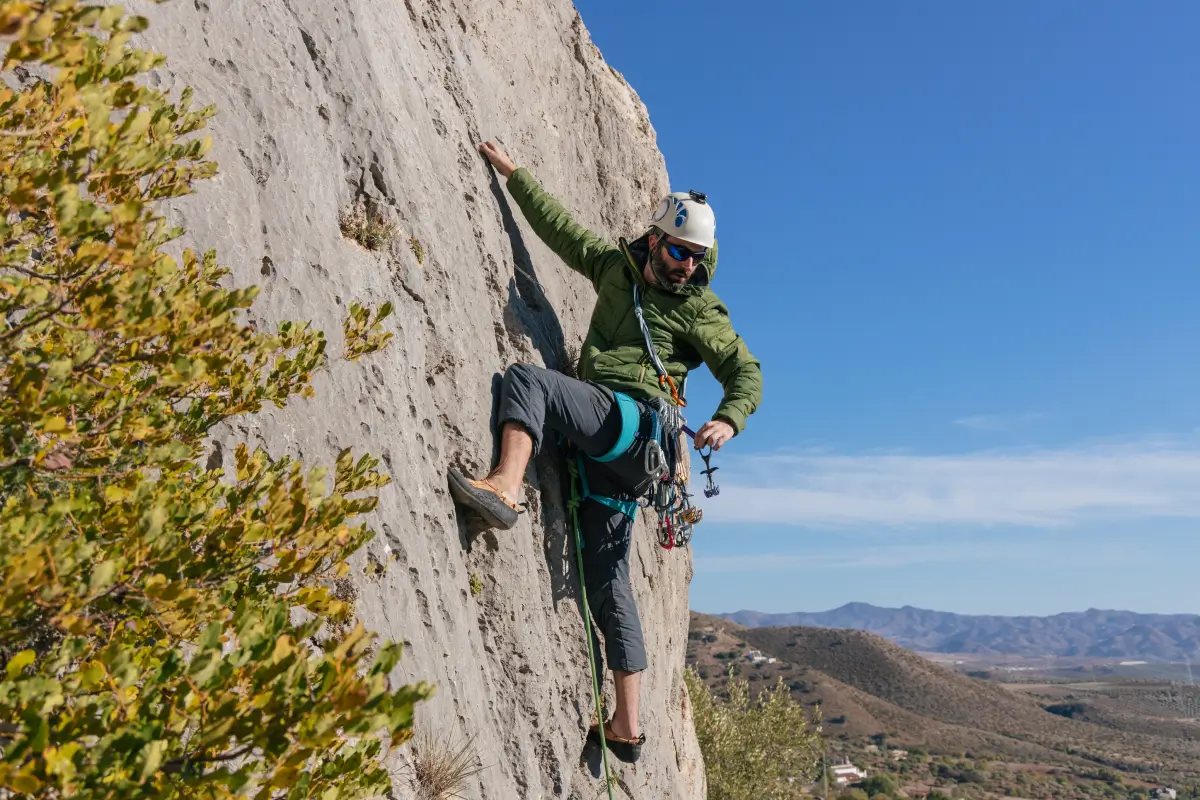 man in black t-shirt and orange shorts climbing brown rock formation during daytime